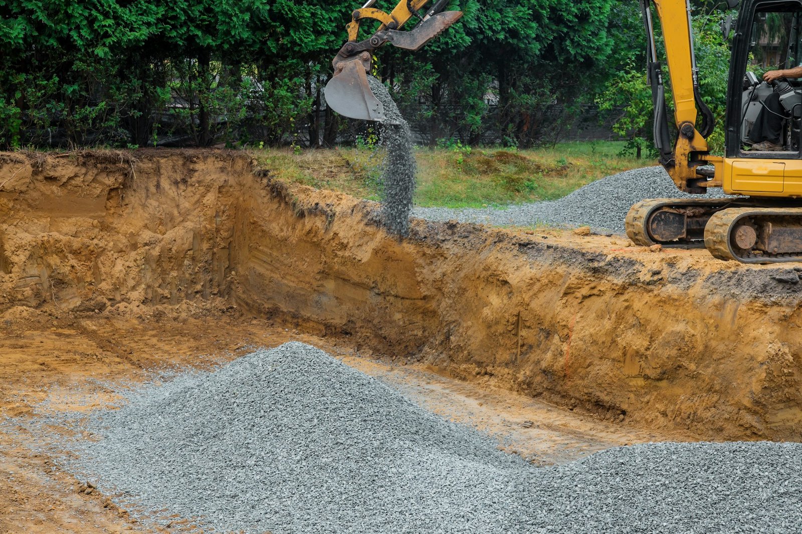 Backfilling trench for the gravel stones at construction site in excavator backfill of foundation