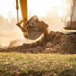 Backhoe working by digging soil at construction site. Crawler excavator digging on demolition site.